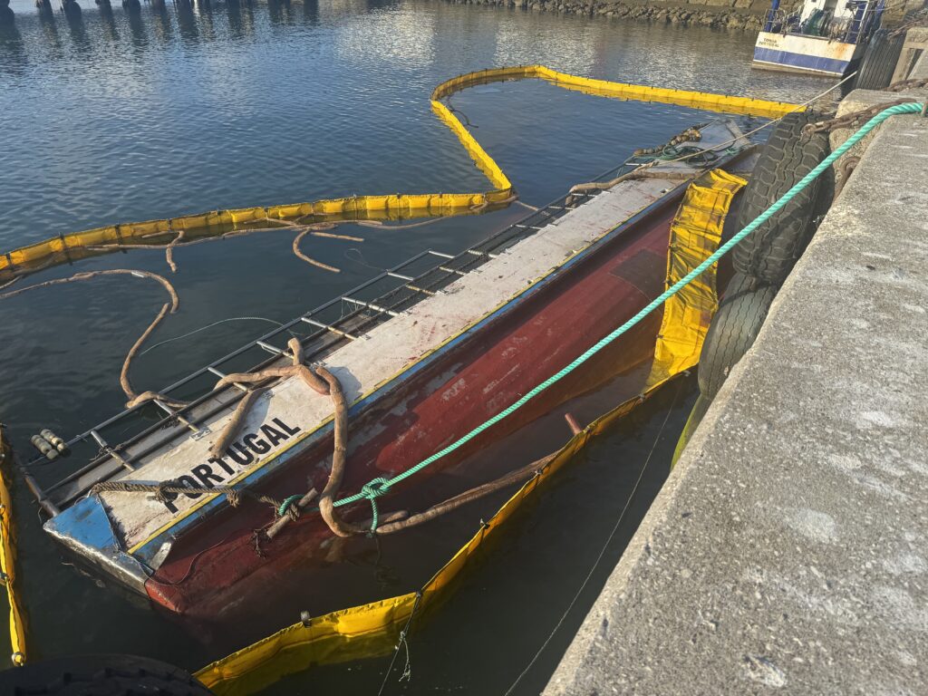 The fishing vessel Amuras sunk alongside in the fishing port of Figueira da Foz, inside containment booms